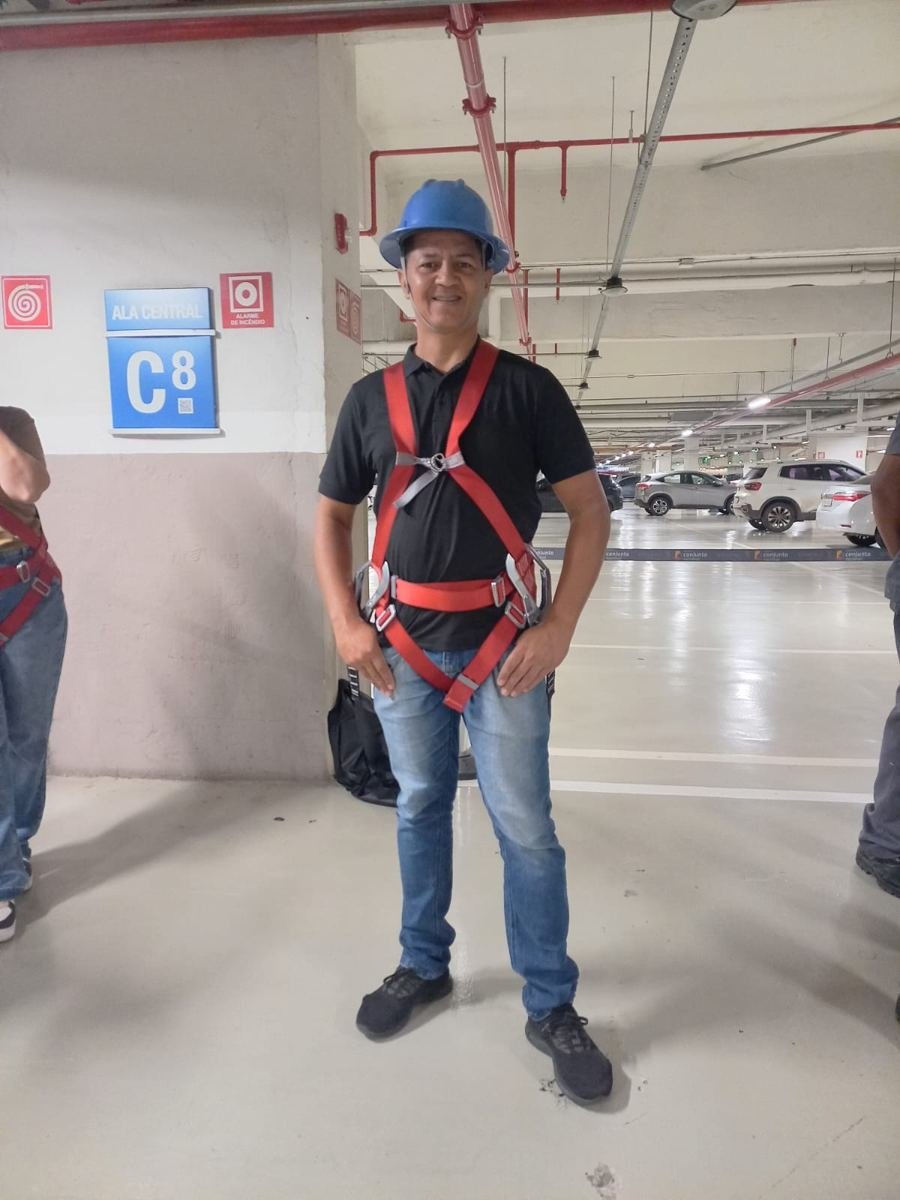 Eletricista da Só no Braço com cinto de segurança em garagem de prédio comercial